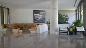 Eine moderne Lobby mit einer großen Säule, Sitzbereichen und einem gerahmten Kunstwerk an der Wand.