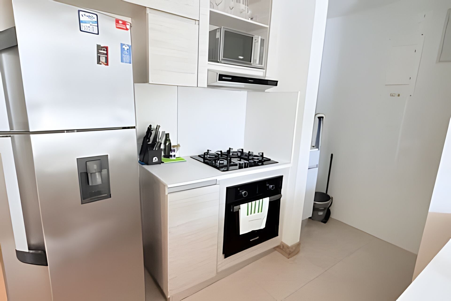 A compact kitchen with a refrigerator, microwave, stove, and oven.