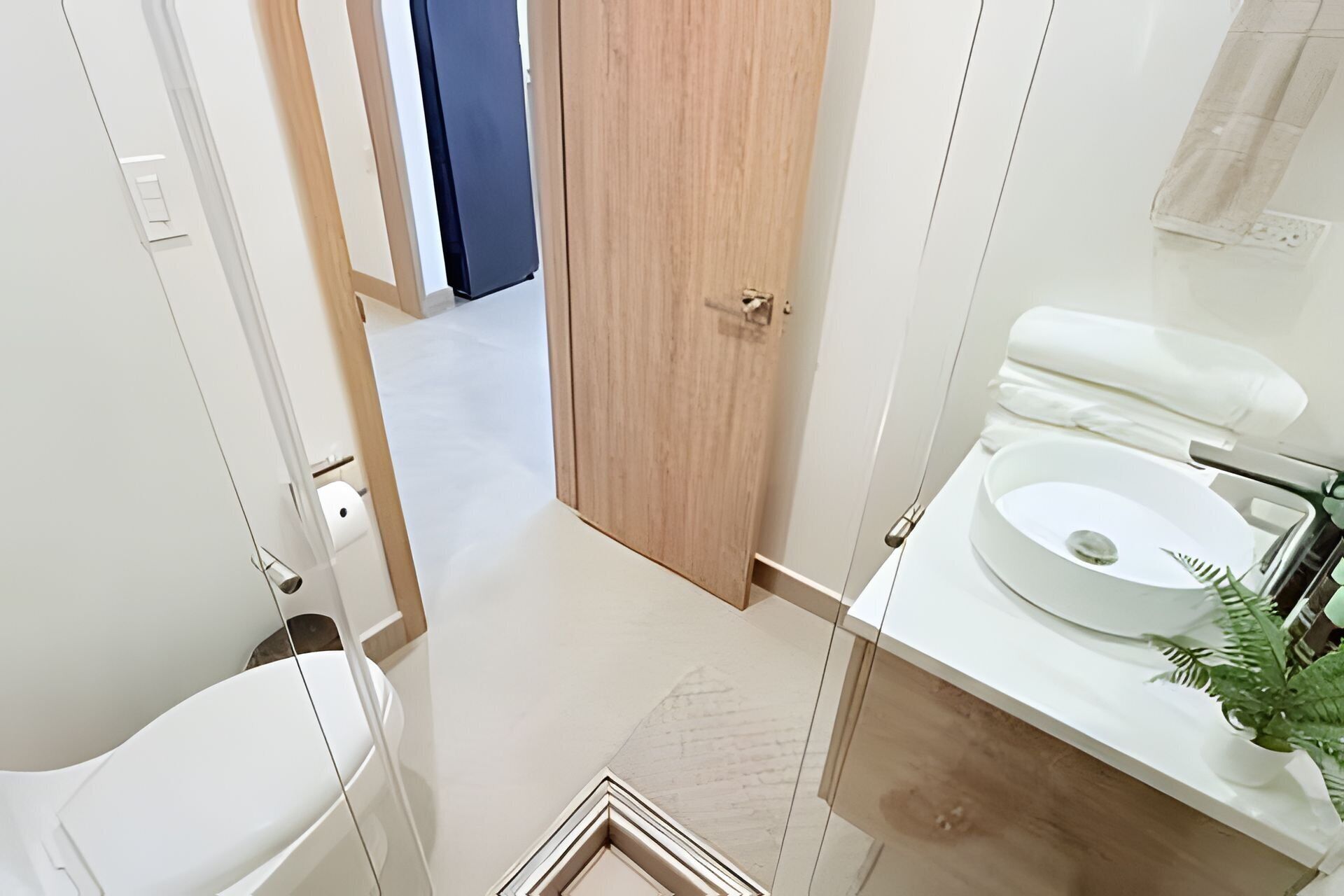 A bathroom with a white sink, a mirror, and a door leading to another room.