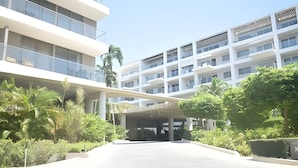 Ein modernes, mehrstöckiges Hotel mit überdachtem Gang und üppiger Bepflanzung.