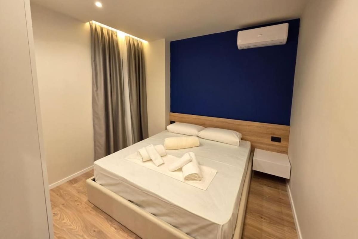 Camera d'albergo con un letto, tende, un condizionatore d'aria e pavimento in legno.