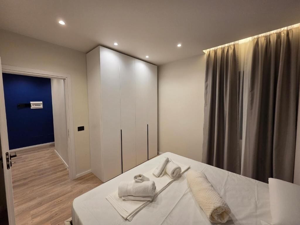 A hotel room with a bed, a wardrobe, a bathroom, and a view of the outside.
