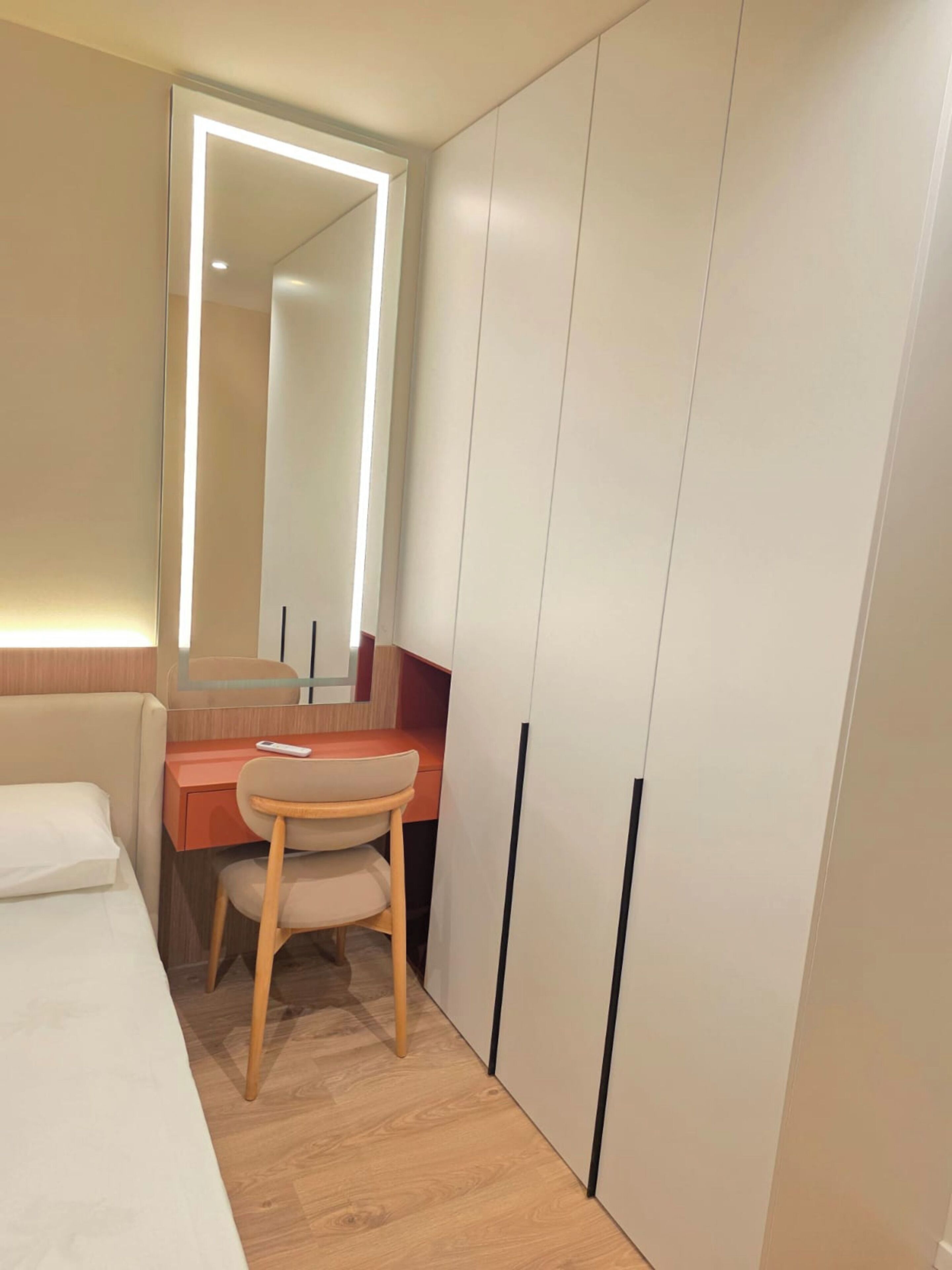 Ein Schlafzimmer mit Bett, Schreibtisch, Stuhl, Spiegel und Kleiderschrank.