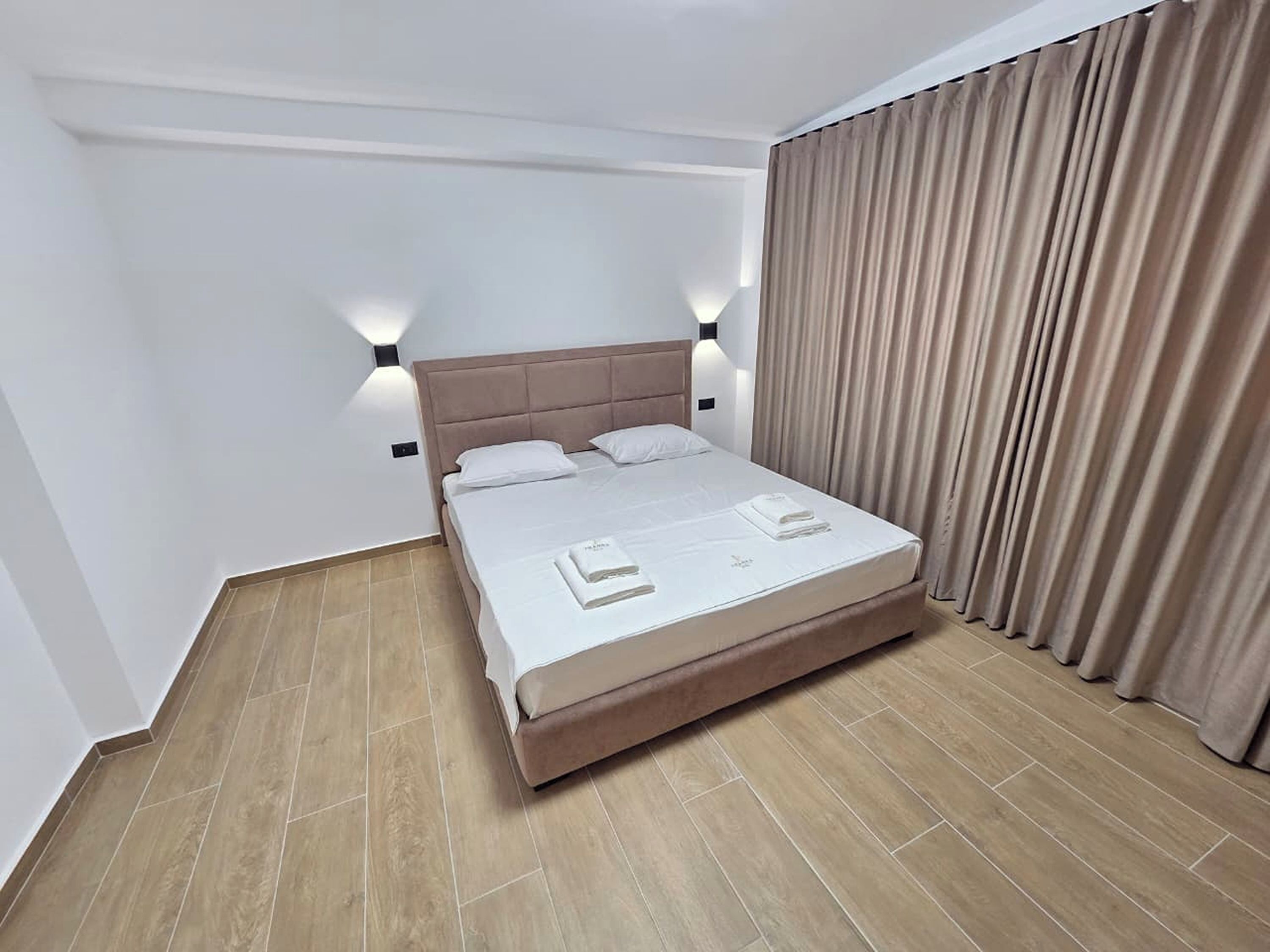 Una habitación de hotel con cama, cortinas y una lámpara.