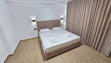 Una habitación de hotel con cama, cortinas y una lámpara.