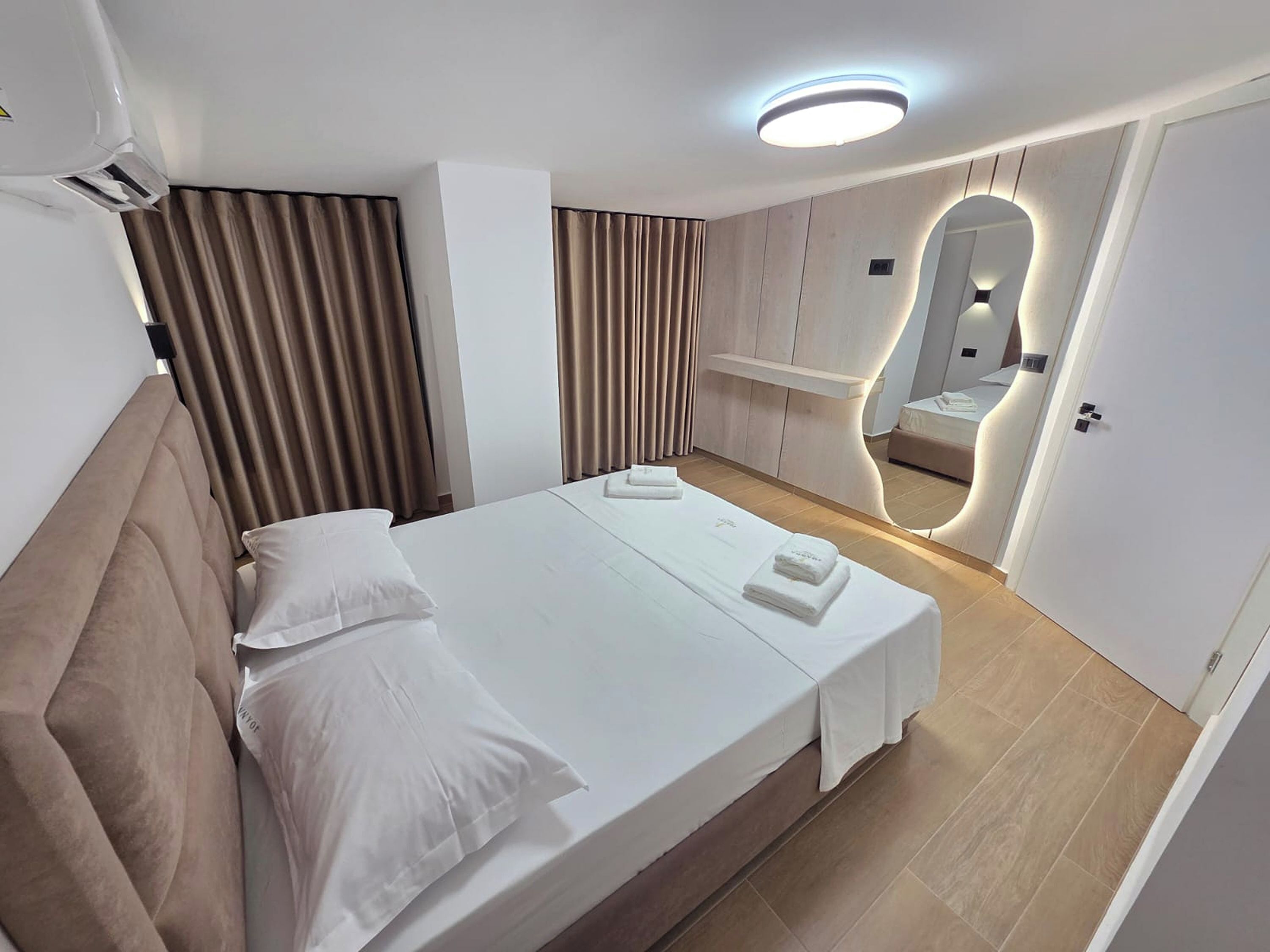 Een hotelkamer met een bed, een spiegel en een wandplank.