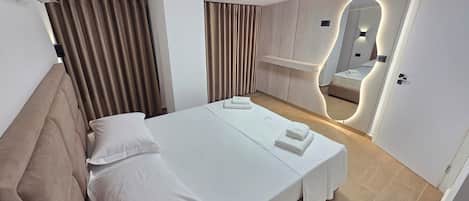 A hotel room with a bed, a mirror, and a wall-mounted shelf.