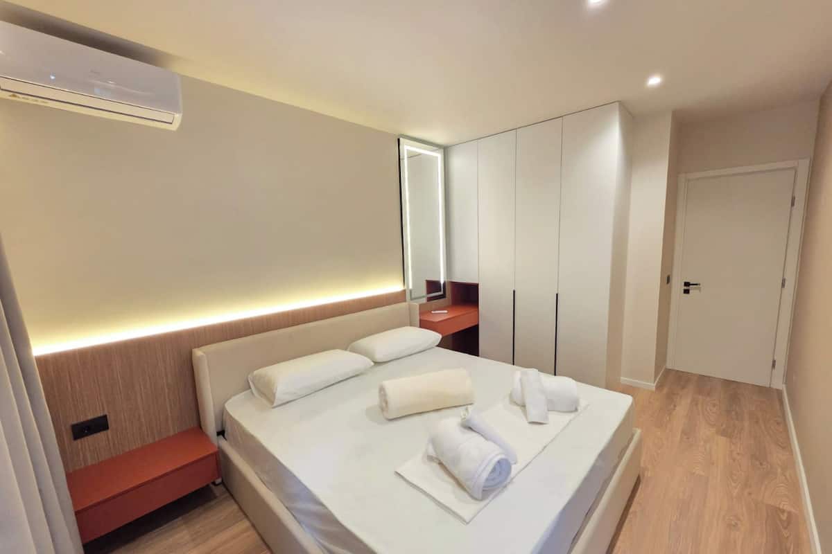 Una habitación de hotel moderna con cama, mesita de noche y armario.
