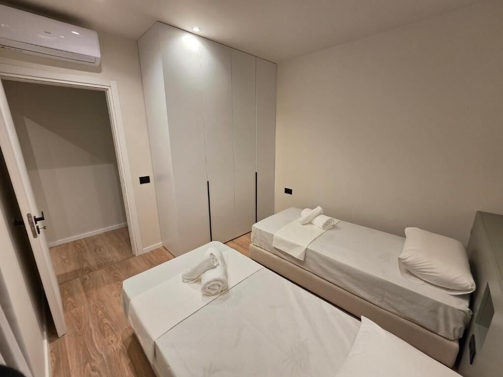 A hotel room with two beds, a wardrobe, and an air conditioning unit.