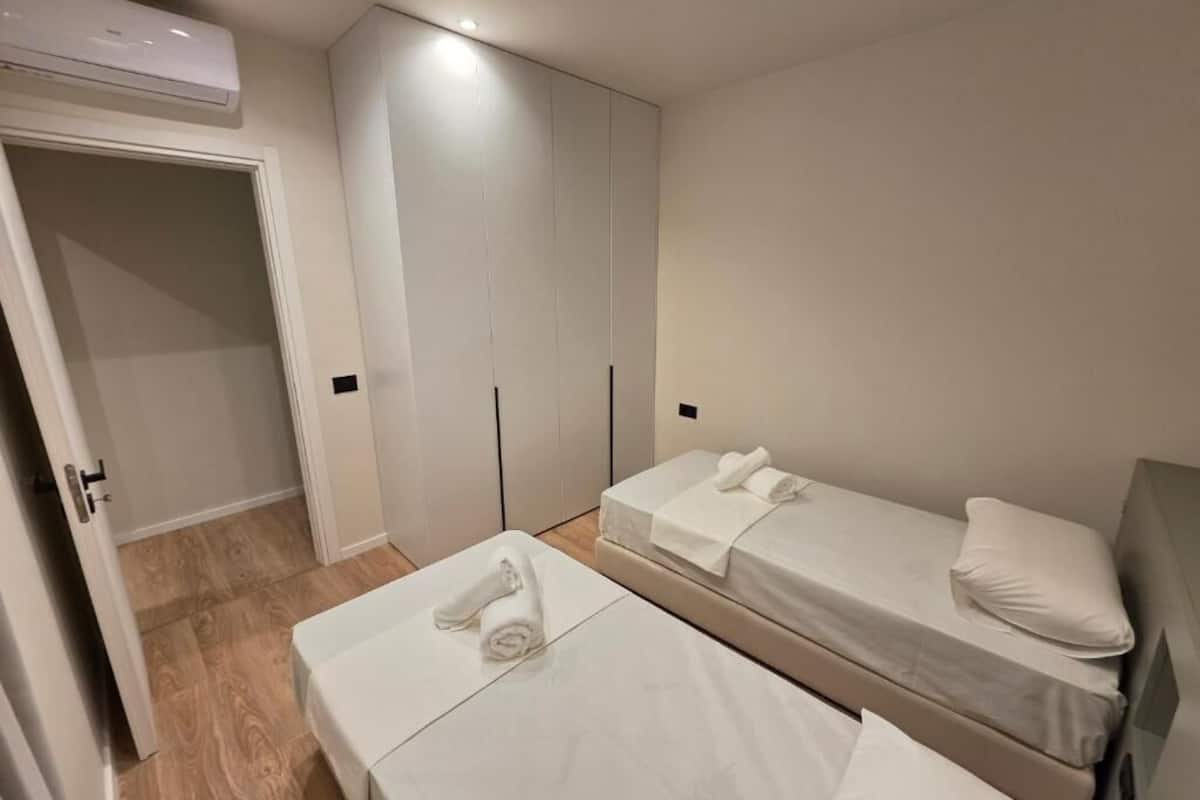 Una habitación de hotel con dos camas, un armario y un equipo de aire acondicionado.