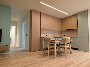 Een moderne keuken met houten kastjes, een eettafel met stoelen en een zichtbare spoelbak.