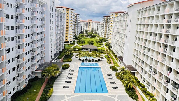 Un ensemble immobilier résidentiel comprenant plusieurs immeubles d’appartements, une piscine centrale et des espaces verts bien entretenus.