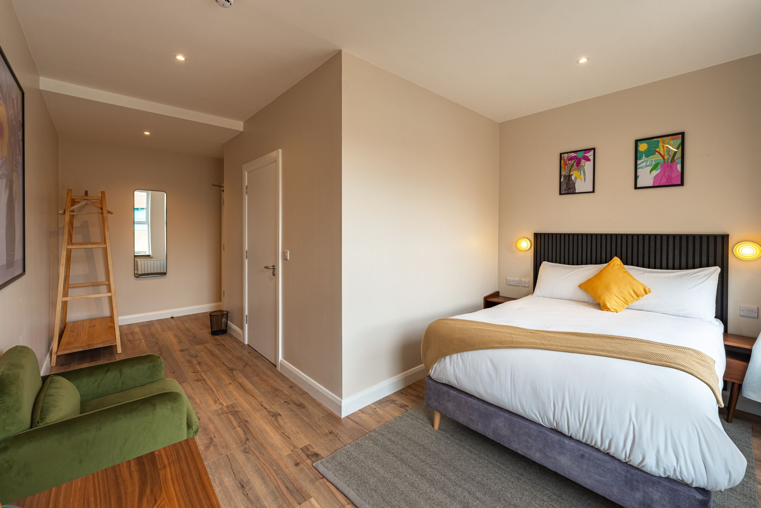 A bedroom with a bed, a green chair, a ladder, and a door.