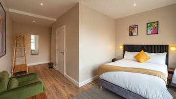 A bedroom with a bed, a green chair, a ladder, and a door.