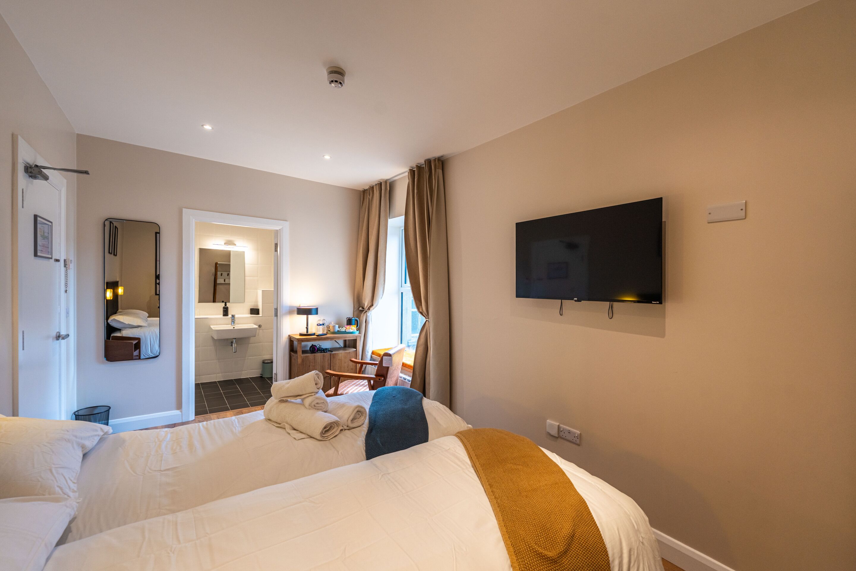 Une chambre d’hôtel équipée d’un lit, d’une télévision, d’une salle de bain et d’un bureau avec une chaise.