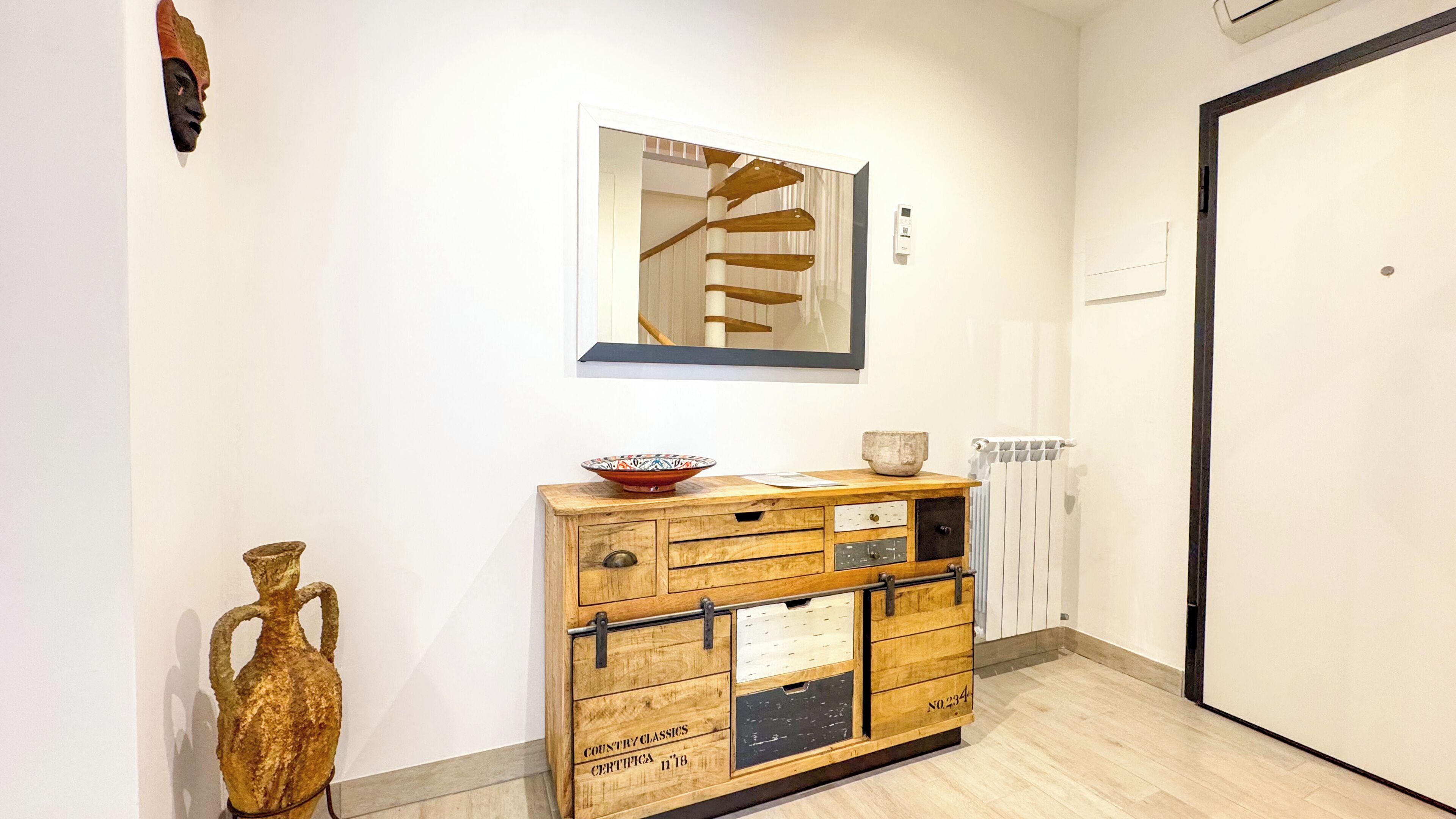 Un corridoio con un mobile in legno, un vaso e un quadro appeso al muro.
