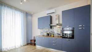 Eine moderne Küche mit blauen Schränken, einer Marmor-Spritzschutzwand und einem Einbauofen.