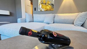 A modern living room with a grey sofa, a mounted abstract painting, and a bottle on a metallic stand. - #3 Design Panorama Apartment, BBQ, 6 guests (Arzl)