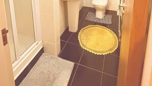 A bathroom with a shower, sink, toilet, and a small rug on the floor. - Room-charming Double Bedroom With Stunni (Wexford)