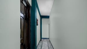 A corridor with a door labeled 'P 111,' a fire extinguisher, and a marble-patterned floor. - Super Townhouse Howell Crossway Shillong (Shillong)