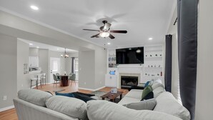A modern living room with a sofa, a television, and a fireplace. - 4 Bedroom House with Fast Wifi, Game Room, Fireplace, 2 King Beds, Grill, Office (Montgomery)