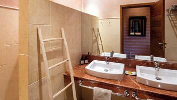 A bathroom with two sinks, a mirror, a towel rack, and a wooden ladder.