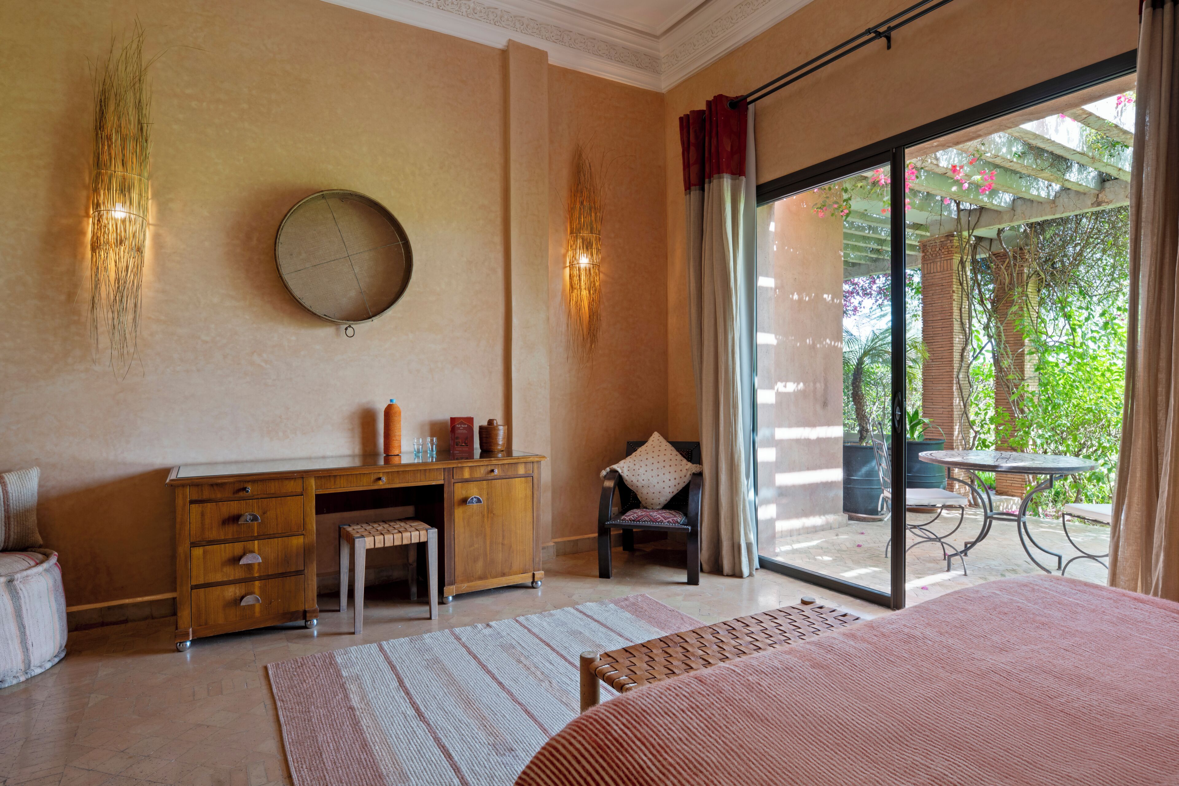 Une chambre à coucher comprenant un lit, un bureau, une chaise, une grande fenêtre et une vue sur la verdure.