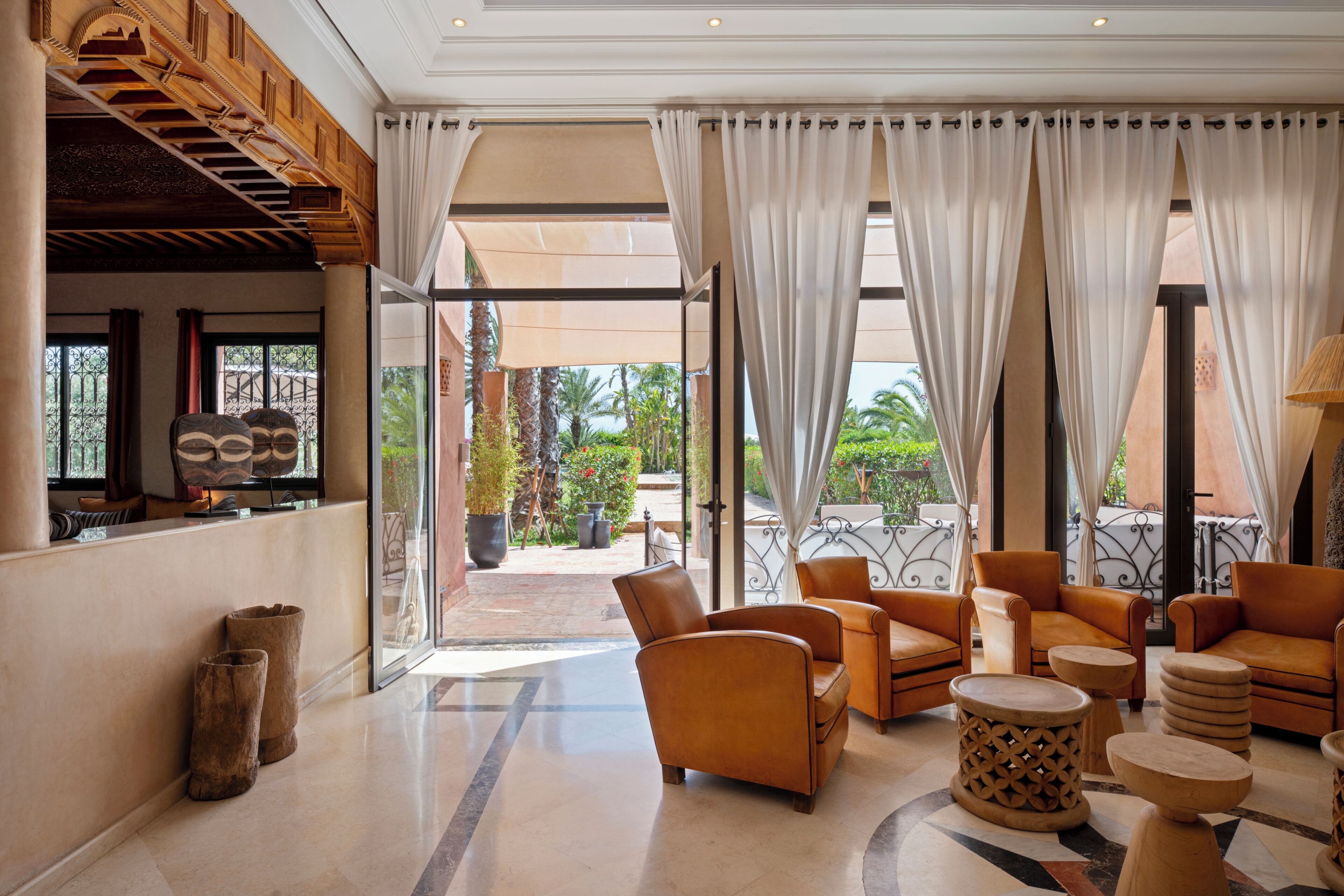 Un vestíbulo de hotel con sofás de cuero, una mesa de centro y vistas al exterior.