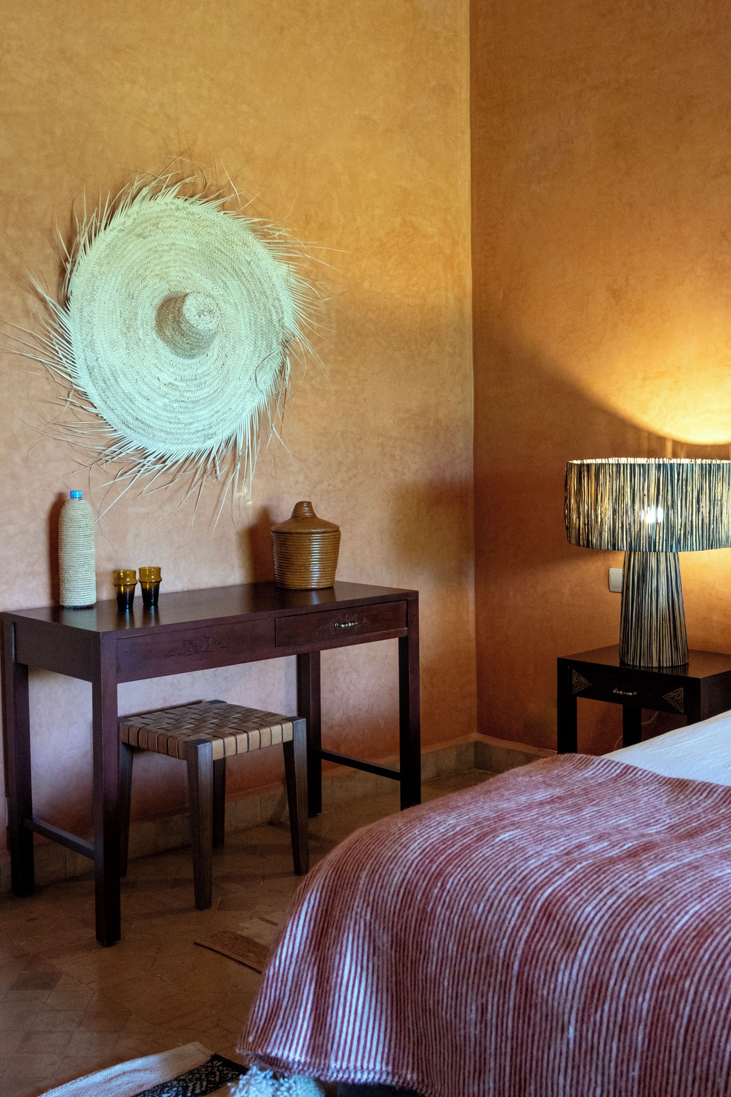 Ein Hotelzimmer mit einem Bett, einem Schreibtisch mit Stuhl, einer Lampe und einem Wanddekor.