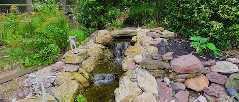 A garden with a small waterfall, rocks, and statues.