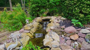 Een tuin met een kleine waterval, rotsen en beelden.