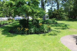 A well-maintained garden with a variety of plants and a gazebo. - Peaceful 3BR Garden Cottage Long Island Escape (Coram)