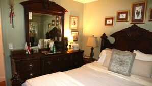 Une chambre d’hôtel avec un grand lit, une commode, un miroir et des tableaux encadrés au mur.