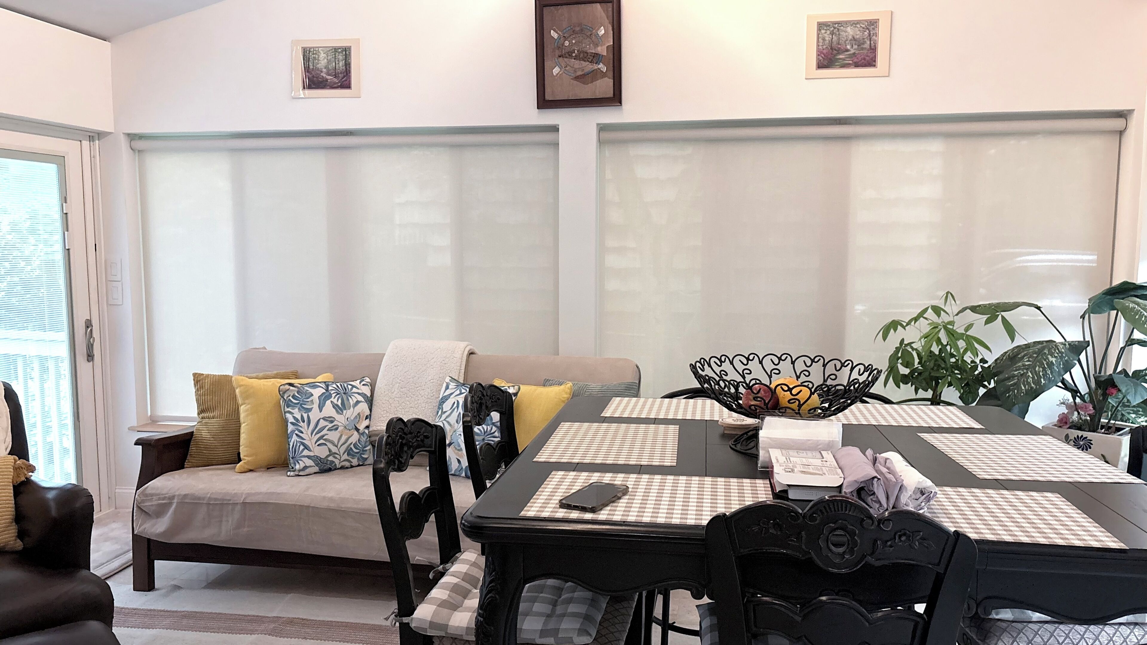 Un comedor con una mesa preparada para dos personas, un sofá con cojines y una ventana con persianas.