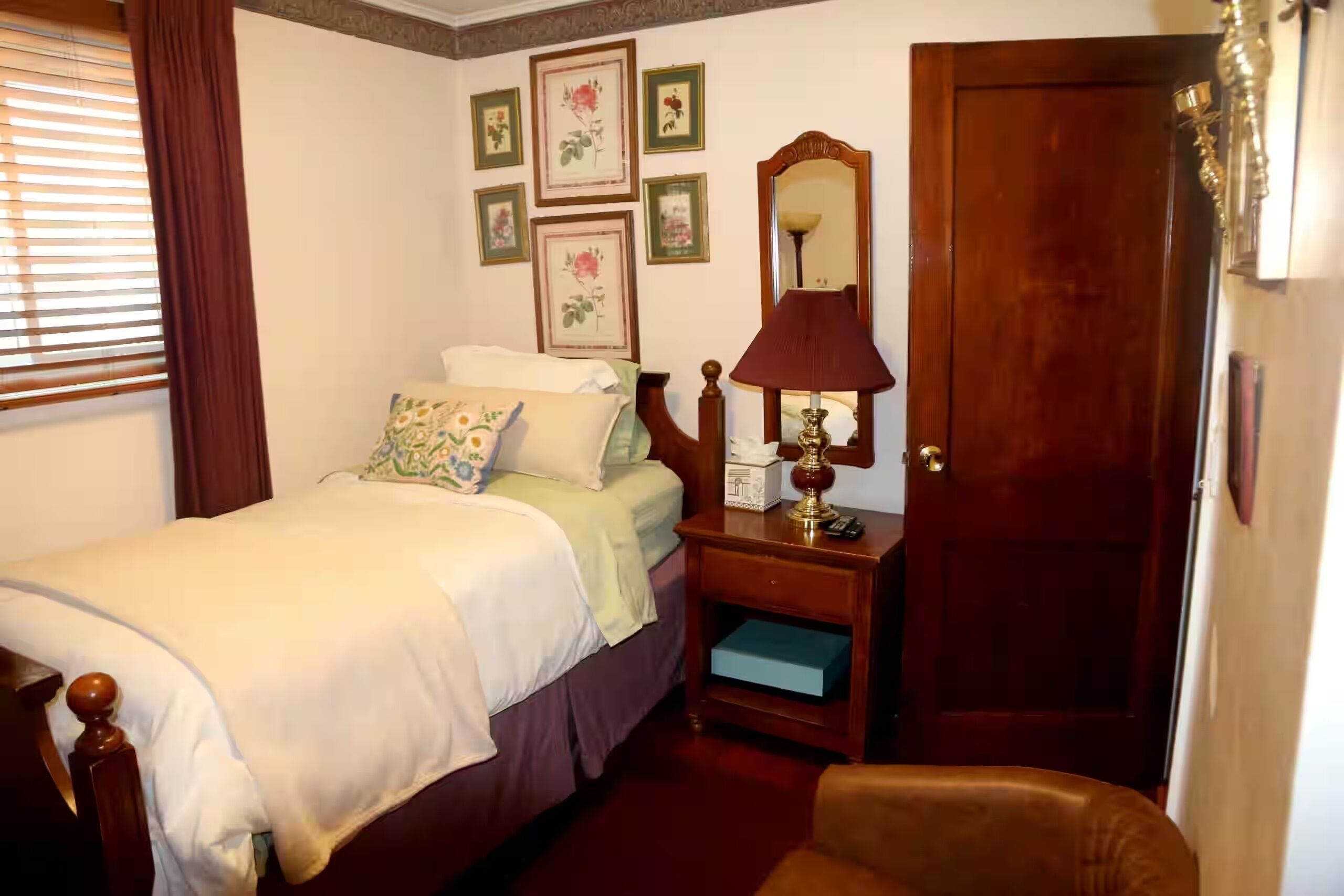 A bedroom with a bed, bedside table, lamp, and a door.