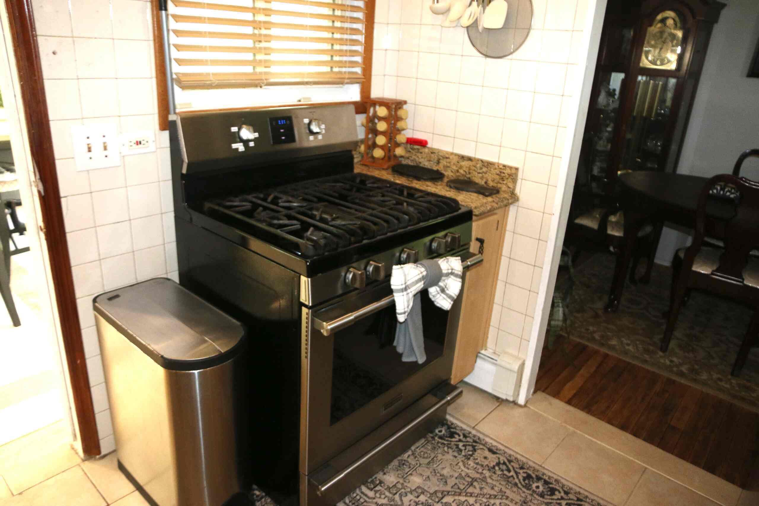 A kitchen with a stove, oven, and a trash can.