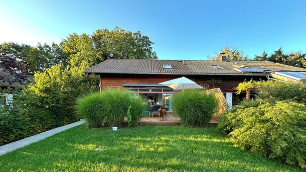 A house with a tiled roof, a covered patio, and a well-maintained lawn. - Wonderfully private vacation home near the lake on Lake Chiemsee with large garden & terrace (Gstadt am Chiemsee)