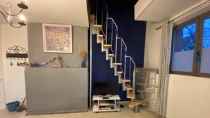 Un salon avec un escalier, une petite table sur laquelle est posée une bougie, une statue décorative et une œuvre d’art encadrée au mur.