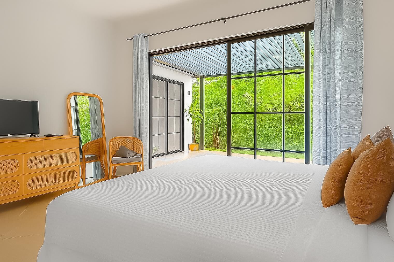 Une chambre avec un grand lit, un téléviseur posé sur une commode en bois, une chaise et une vue sur la verdure grâce à de grandes fenêtres.