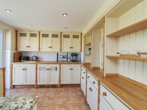 A kitchen with white cabinets, a wooden countertop, and a tiled floor. - Highfields (Newark)