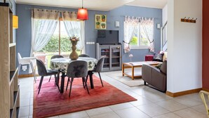 Un coin repas comprenant une table, des chaises, un vase avec des fleurs et un tapis rouge.