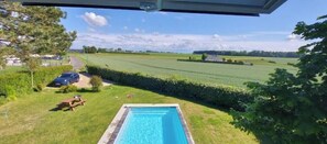 Una piscina con vistas a un campo verde y un coche al fondo.