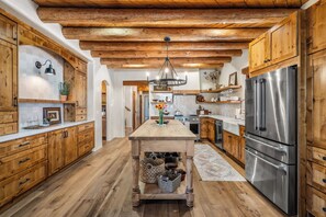 A kitchen with wooden cabinets, a central island, stainless steel appliances, and a hanging light fixture.
