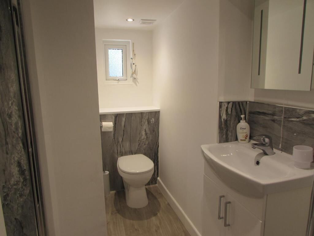 A bathroom with a toilet, a sink, a mirror, and a window.