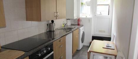 A compact kitchen with a stove, sink, and a small table.