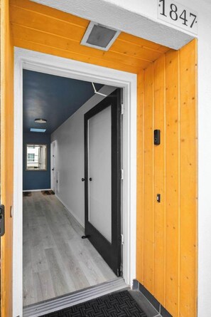 A hallway with a wooden door, a number plaque, and a window. - Mission Hills 2BR | City Views & Covered Parking (San Diego)