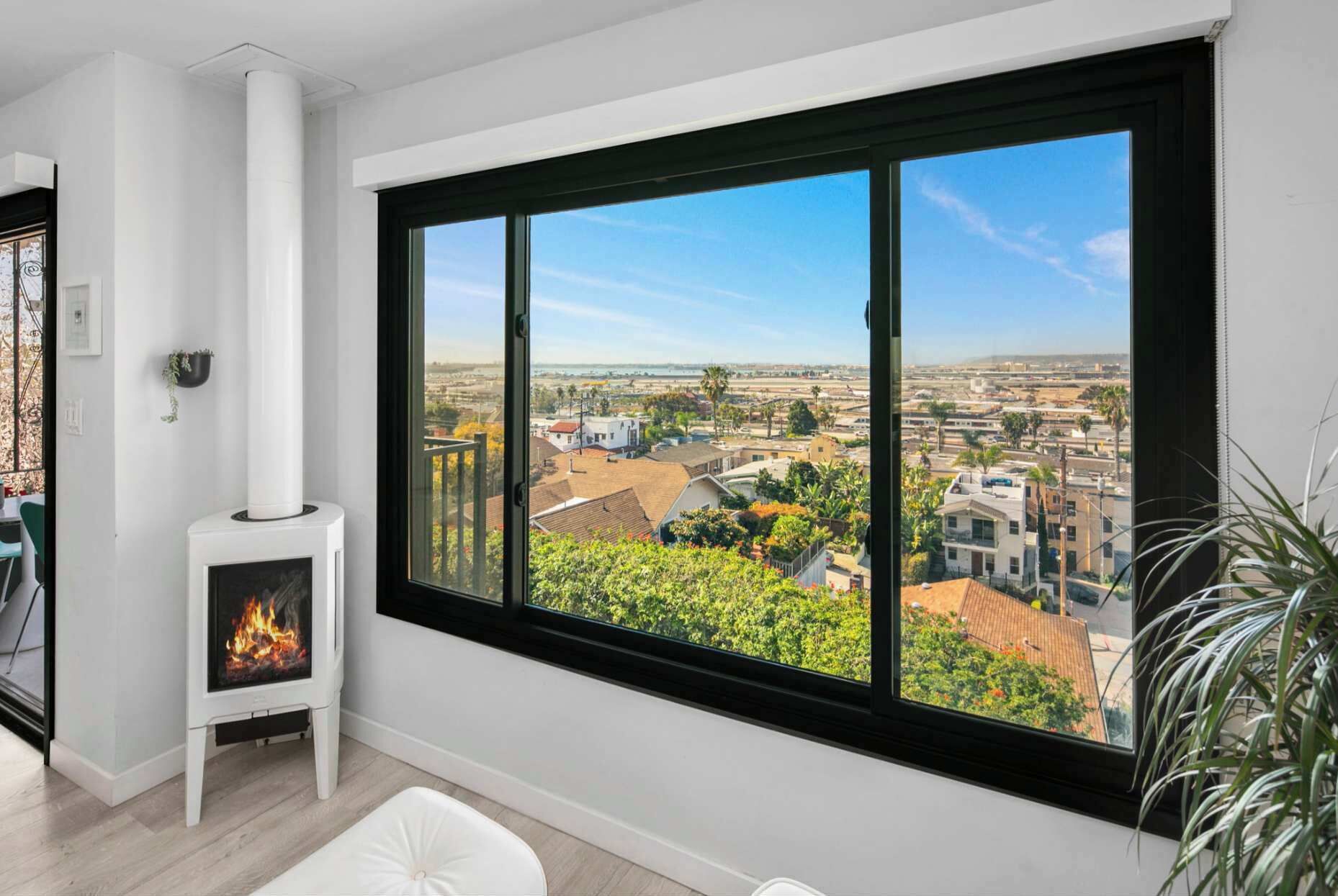 A room with a large window, a fireplace, and a view of a cityscape.