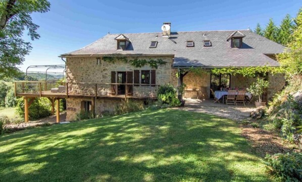 Une maison en pierre dotée d’un patio couvert, d’un petit jardin et offrant une vue sur le paysage environnant.