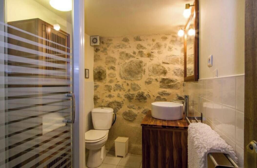 Ein Badezimmer mit Steinwand, Toilette, Waschbecken und Spiegel.