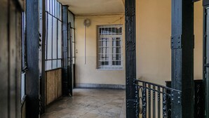 A corridor with a tiled floor, a barred window, and black metal doors. - Panoramic Top-Floor Downtown Apartment with Citadel & Liberty Statue View (Budapest)